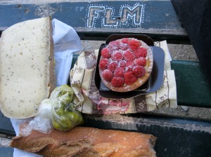 Picnic lunch displayed on a graffitied park bench in Limoges.